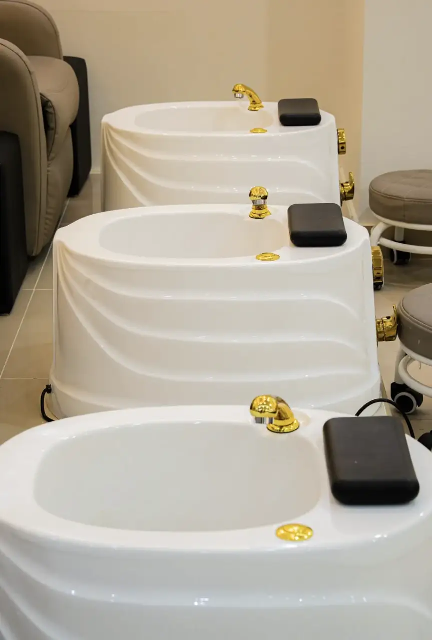 Three white foot-spa bowls with gold taps in a row