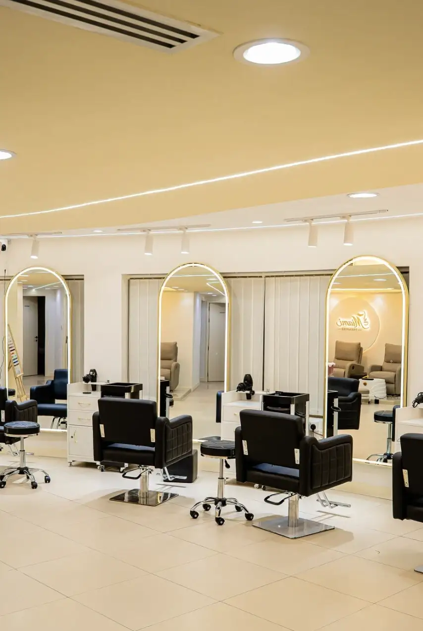 A row of arched, gold-framed mirrors above black styling chairs
